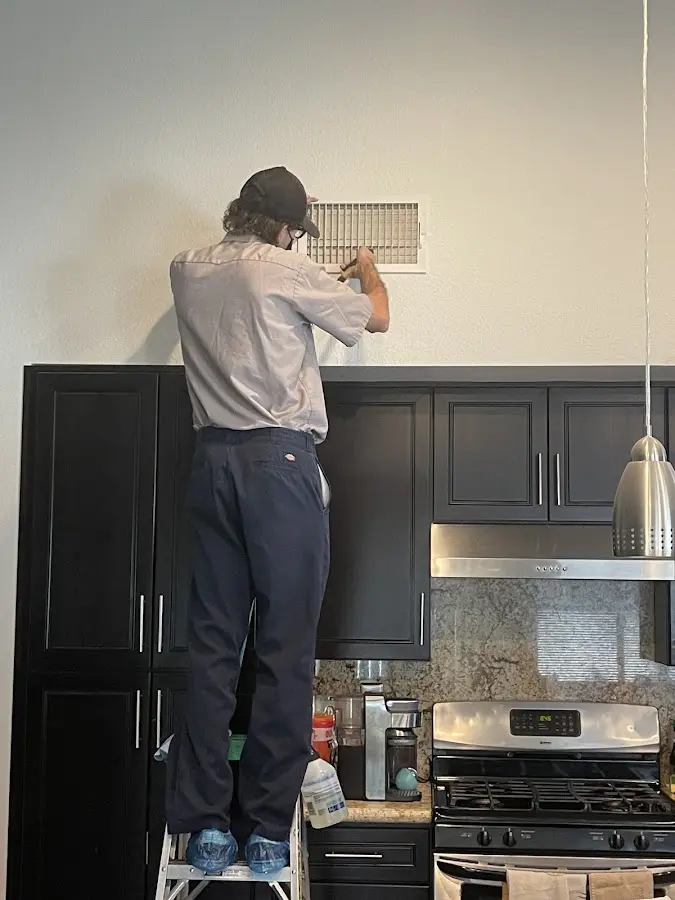 Technician inspecting an air vent during HVAC service in St. Louis Park